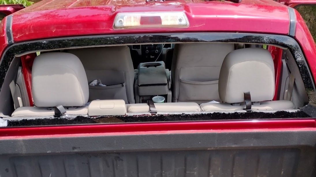Broken rear window on a red Ford F-150 pickup before back glass replacement